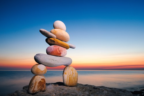 Sunset over the water with stones stacked on each other